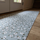 Sea salt blue linen background with tiny white and green flowers on an indoor washable hallway runner placed just inside a set of double doors.