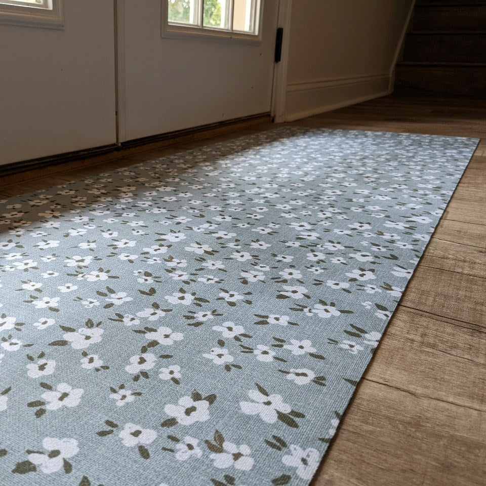 Sea salt blue linen background with tiny white and green flowers on an indoor washable hallway runner placed just inside a set of double doors.