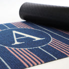 Close up of navy and pink basic stripe monogrammed partially rolled to show rubber textured backing