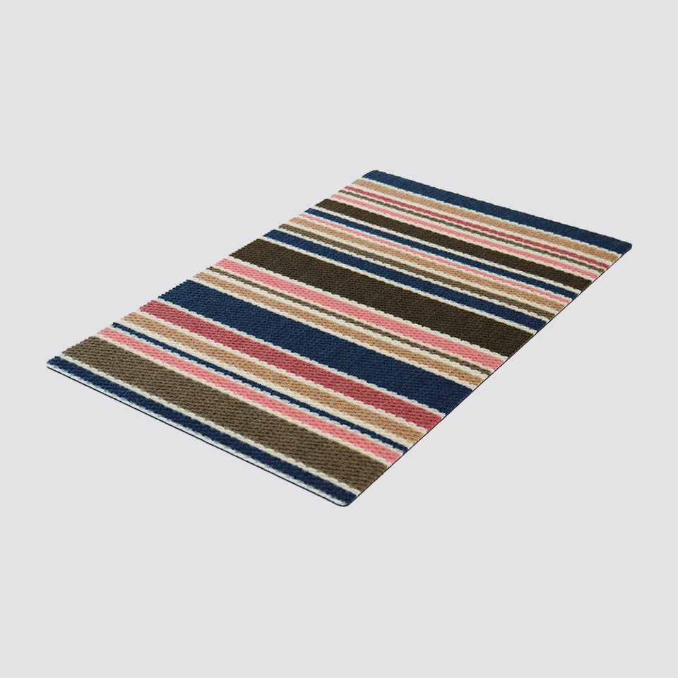 Angled shot of striped doormat with navy tan and pink stripes