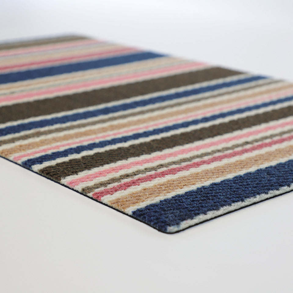 Angled low profile doormat shot of striped doormat in navy pink and brown