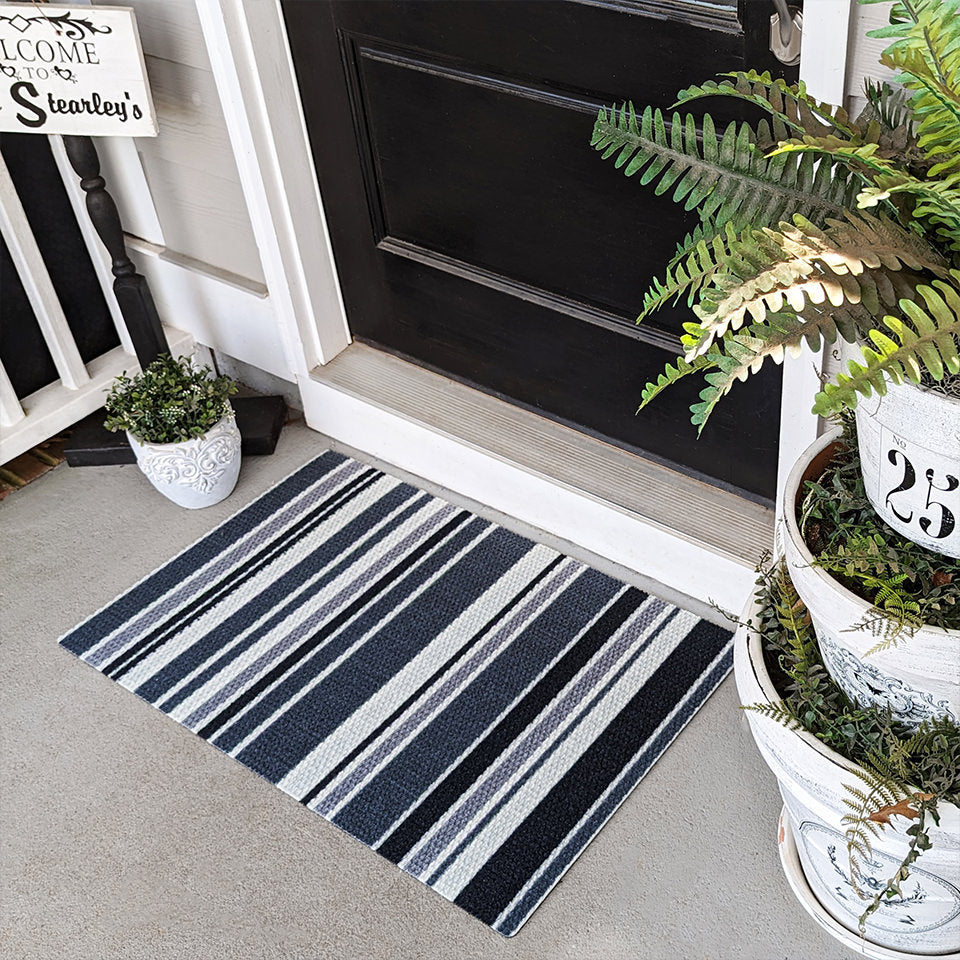 Grey striped doormat in front of black traditional door under covered porch