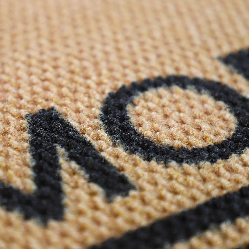 Closeup of non shedding doormat in tan and black personalized with last name