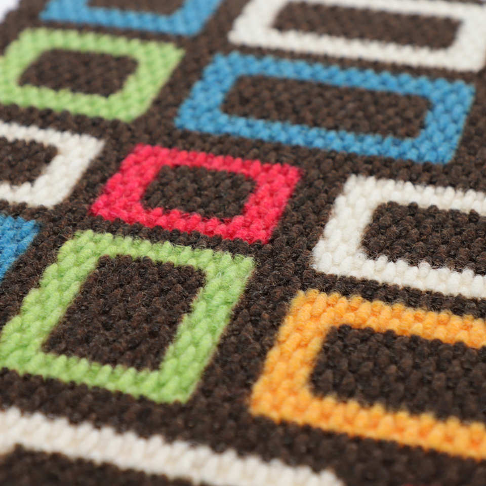 Close up of doormat with retro colorful squares on dark brown background