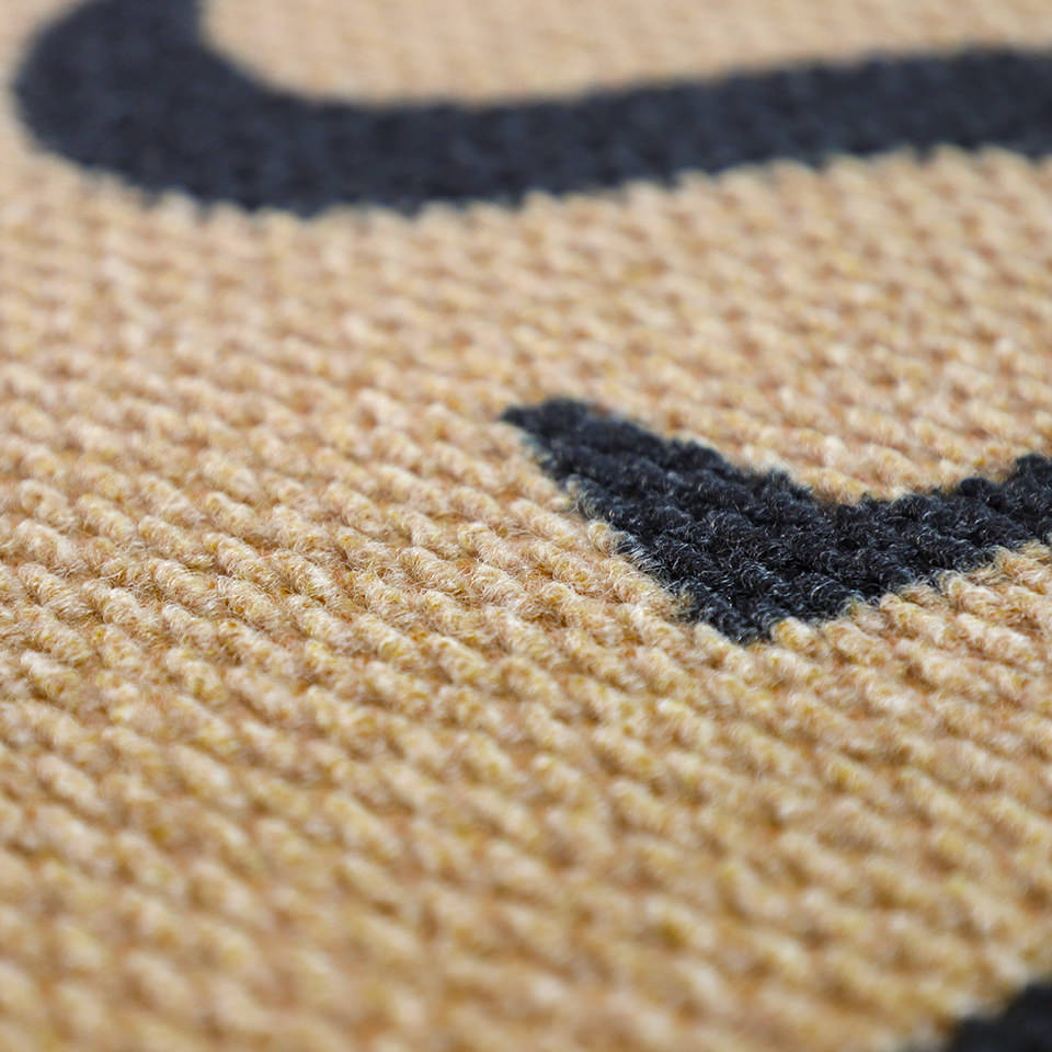 Close up of monogrammed doormat in tan and black
