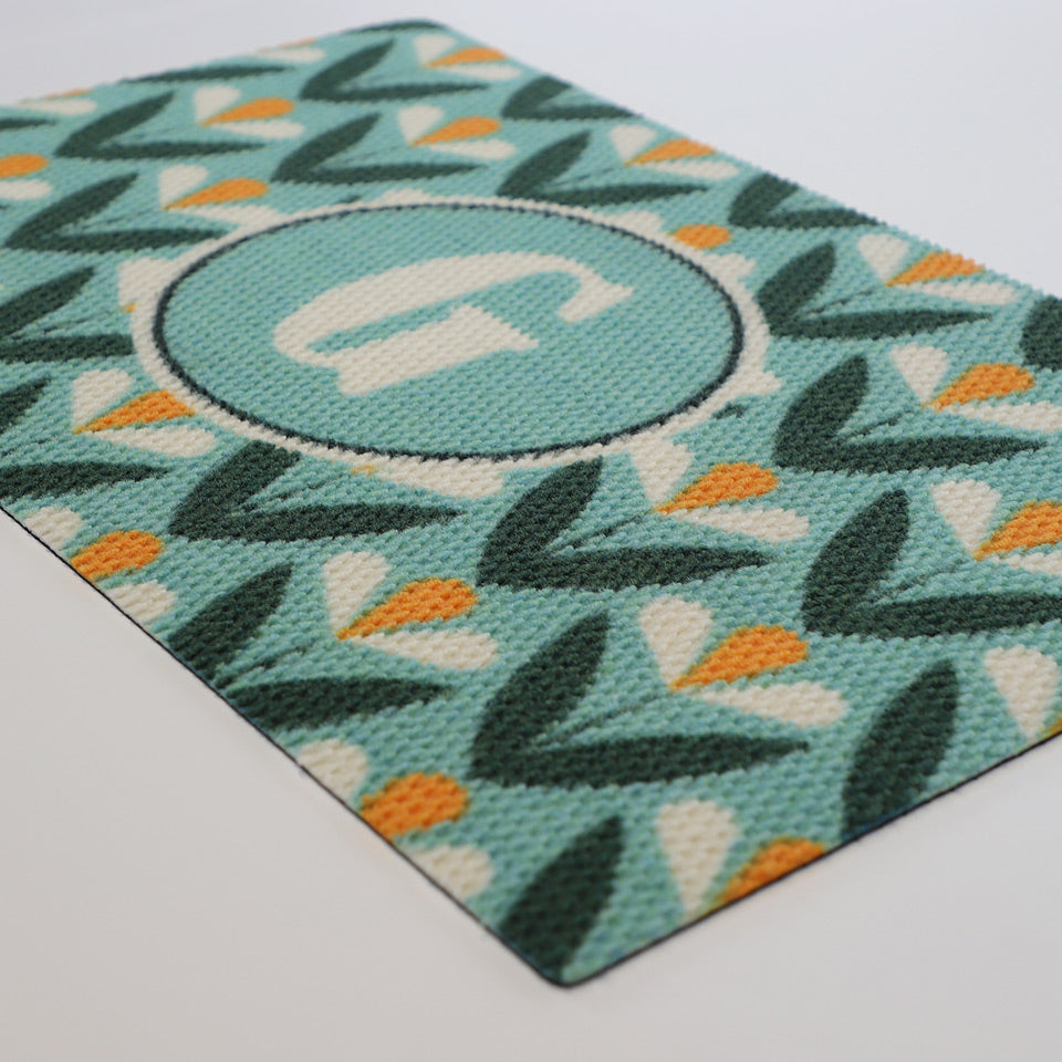 Angle shot of our mid century inspired Spring Blooms floral doormat in aqua green and yellow.  Personalized with your monogram for a customized doormat