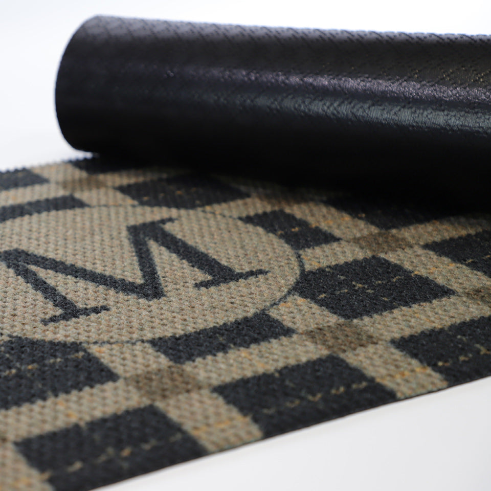 Rubber backed monogrammed low profile doormat in brown and black plaid.