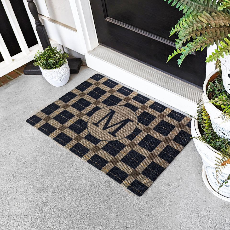 Doormat on porch of black and tan monogrammed entryway mat for a single door.