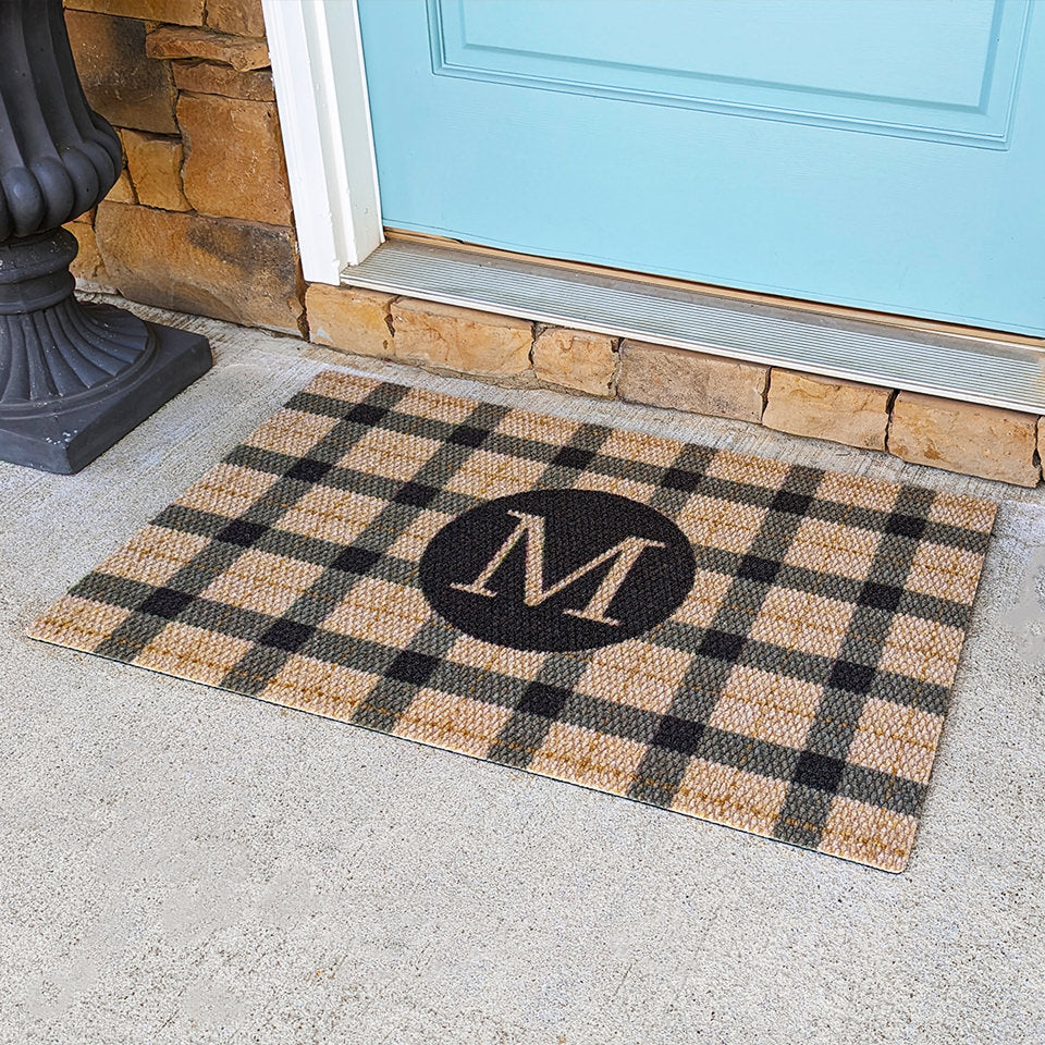 Monogrammed coir and black plaid doormat on front porch in front of door.