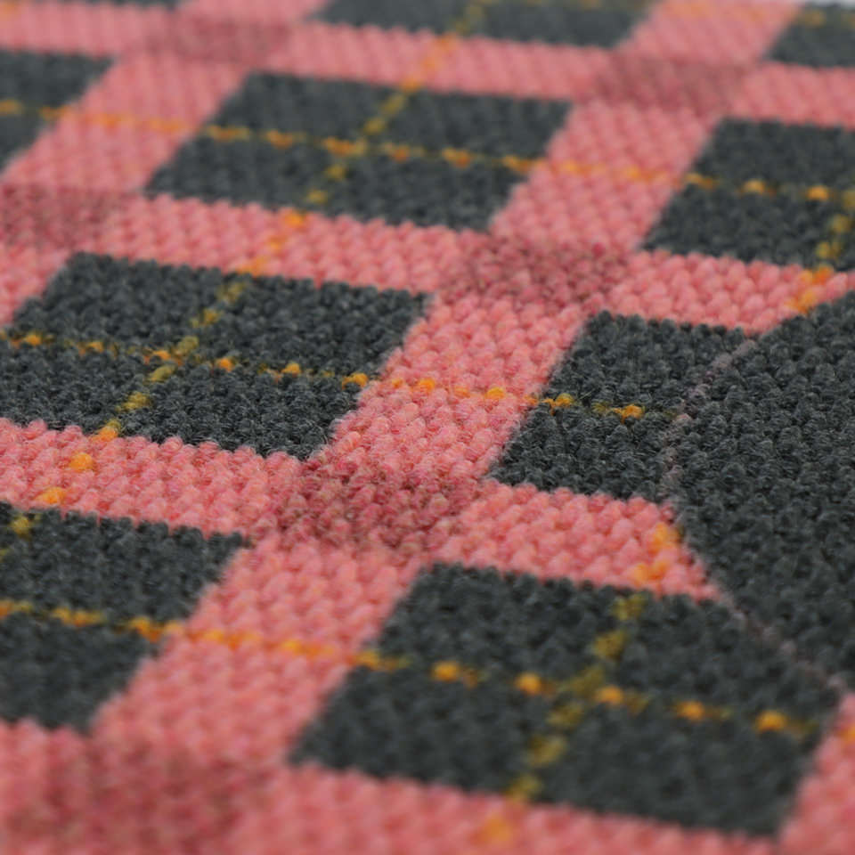Close up of texture for pink, grey, and yellow plaid doormat