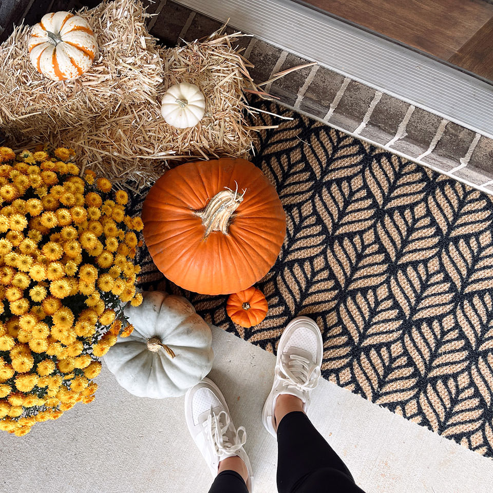 black and coir botanical doormat in front of door with fall decor and pumpkins