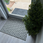 single size black and white diamond dot doormat inside entryway with glass door